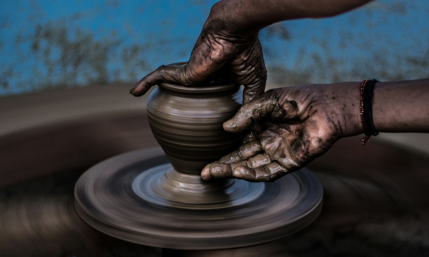 Hands shaping clay on a pottery wheel; illustrative stock photograph